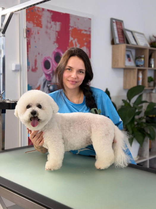 Mitarbeiterin mit einem weißen Hund auf dem Pflegetisch